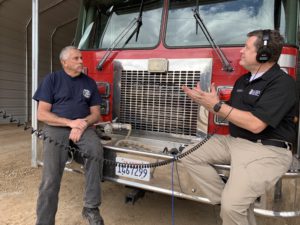Bob Orange and Shawn Boyd sitting on fire truck front bumper