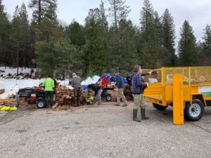 People putting firewood in dump trucks