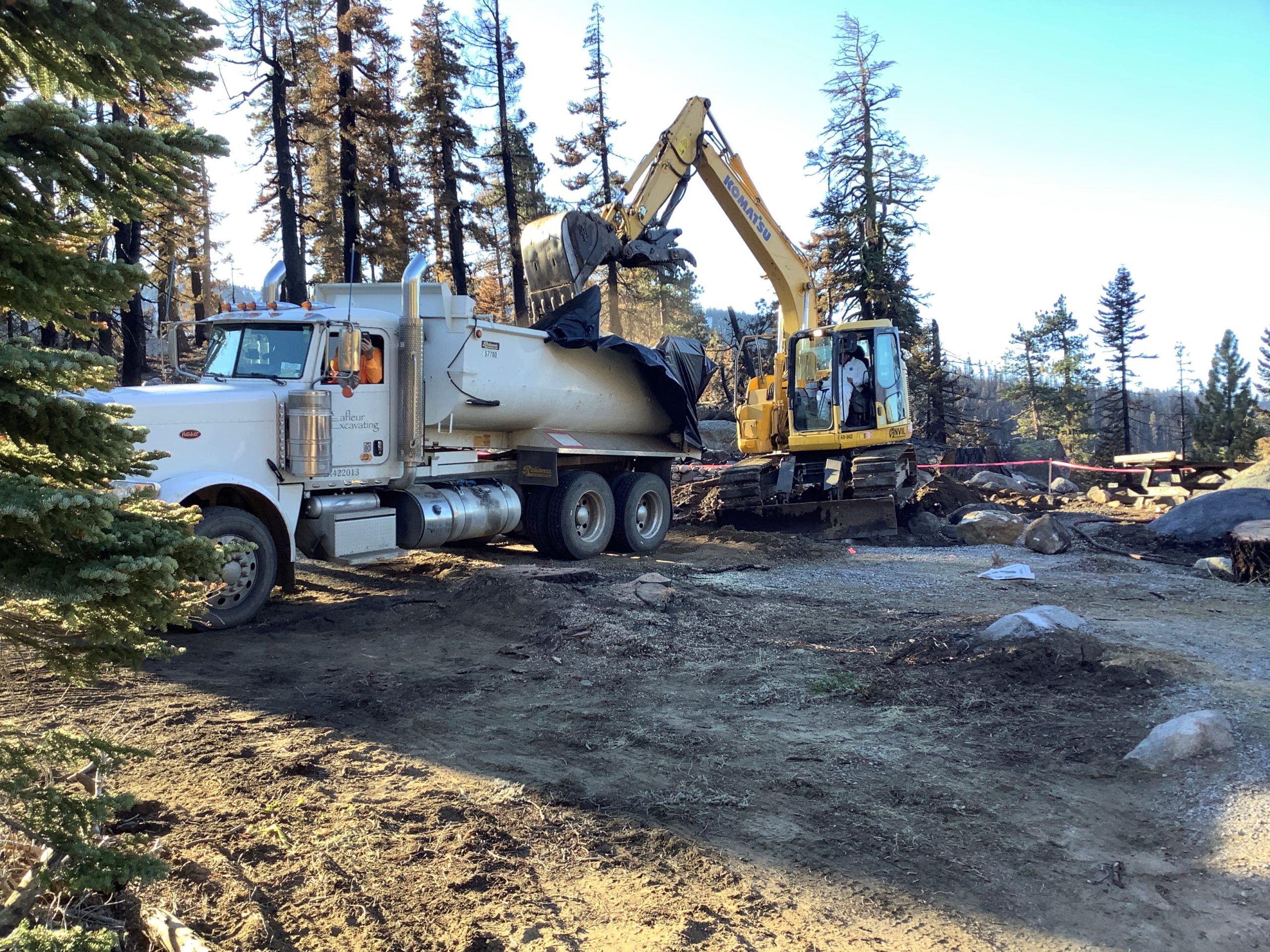 state crews removing fire charred structural debris using a bulldozer