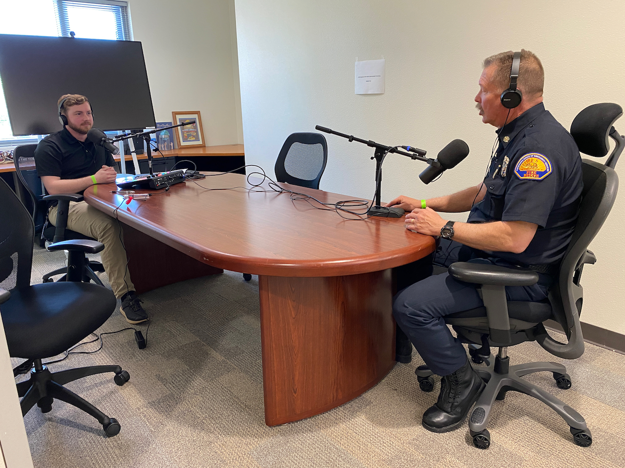 Adam Cranfill and Chief Brian Marshall sitting down at table discussing fire readiness with recording equipment.