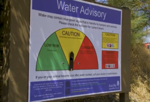 water advisory sign that has green, yellow, and red scales. A small arrow is placed over yellow scale that reads "caution"