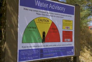 Water information sign with green, yellow and red scales. Above the yellow scale there is a small arrow with the inscription "Caution"