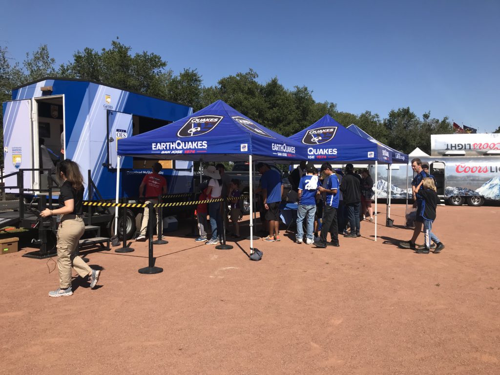 Image of the Shake Trailer with pop up tents in front of it and a crowd of people waiting for their turn to ride it. 