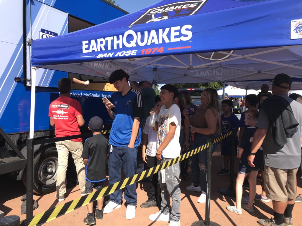 Image of teenagers waiting in line to ride the cal O E S shake trailer under a pop up tent