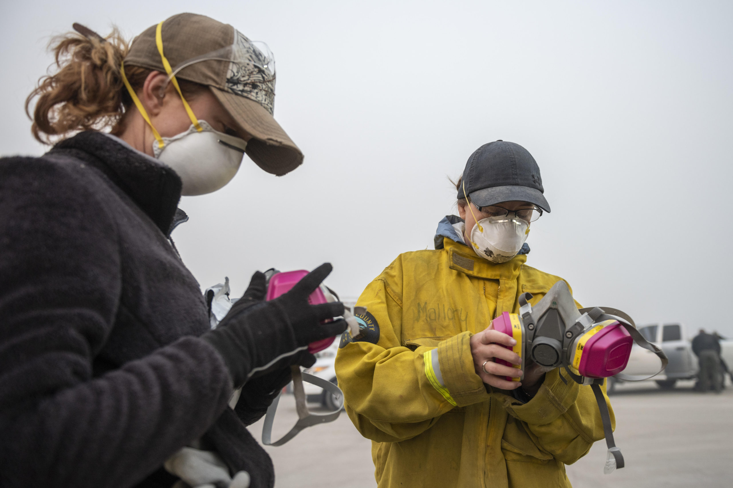 Ashley Kendell (left) Mallory Peters (right) put on air masks as a team of Anthropologists work with the Butte County Sheriff Coroners at the Coroner Incident Command at Butte College to identify human remains consumed by the Camp Fire continues to impact campus carrying heavy smoke over the area on Friday, November 16, 2018 in Oroville, Calif. (Jason Halley/University Photographer/CSU Chico)