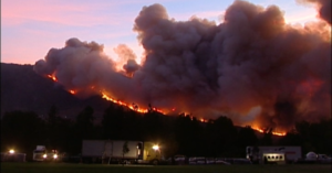 Flames move up a mountain as smoke fills the sky