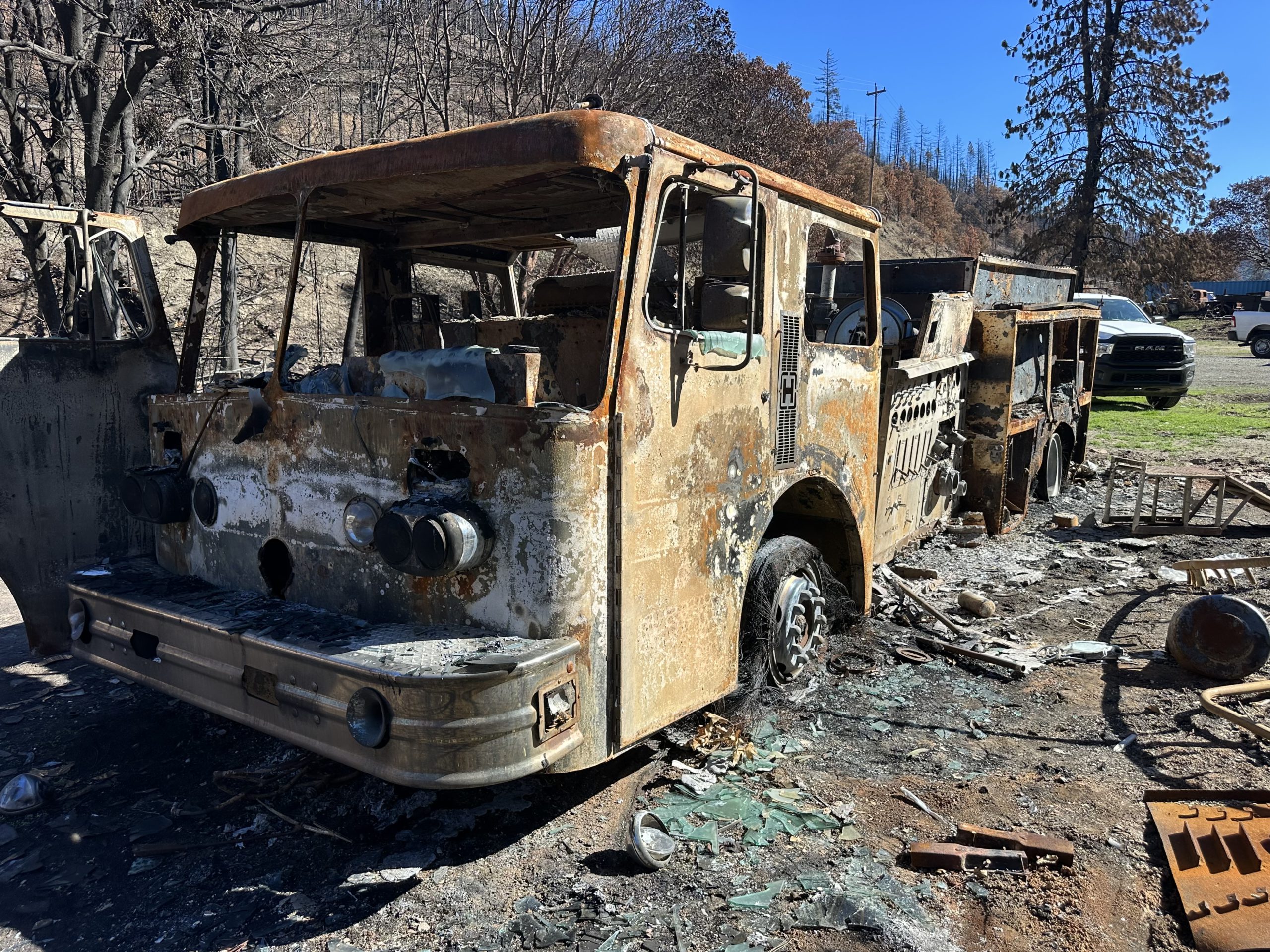A burned bus sitting in the dirt.