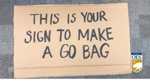 cardboard sign says this is your sign to make a go bag