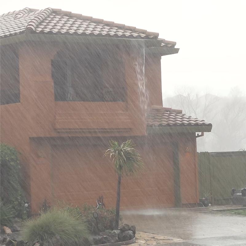 An image of a stucco house and front yard in heavy rain.