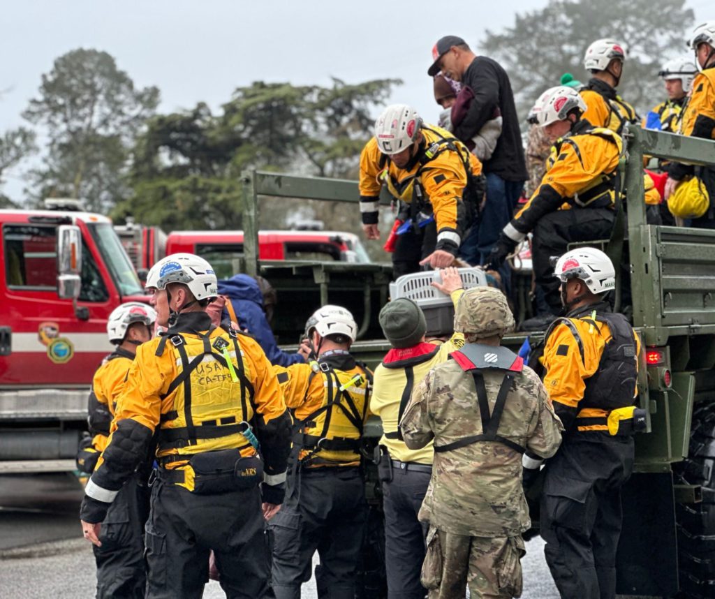 Image of search and rescue responders unloading people and an animal crate from truck.