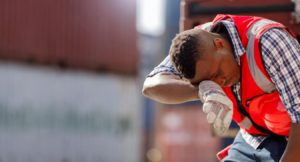 Construction worker wiping his brow while working in hot weather