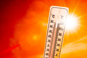 outdoor thermometer over a red and orange sky with sun behind the thermometer.