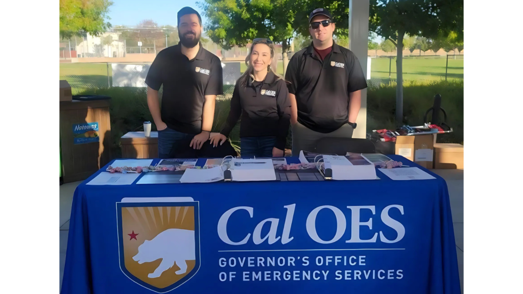 photo of 3 team members in front of table with cal OES cloth